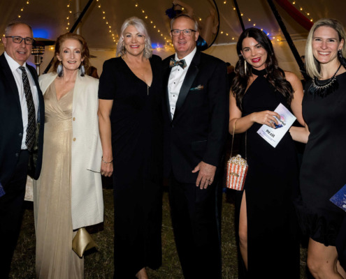 People in formal attire at circus staging event with stage lighting and decorations.