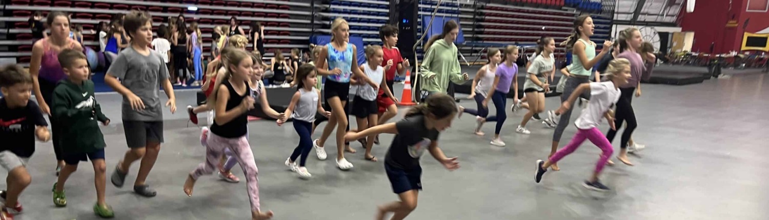 Exercise children participating in circus staging activities in an indoor arena at Circus Arts OSTG.