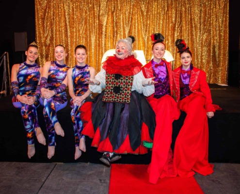 Performance art in circus staging with clown and acrobats on stage.