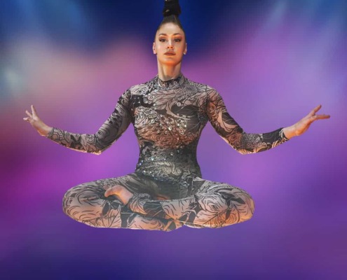 Graceful mime artist practicing balanced yoga pose on colorful stage, highlighting circus arts staging and performance skills.