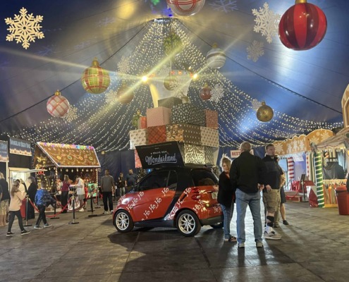 Festive circus tent decorated for Christmas with hanging ornaments and string lights.
