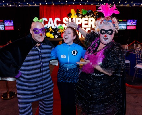 Colorful circus performers in clown costumes at a circus staging event with vibrant stage backdrop.