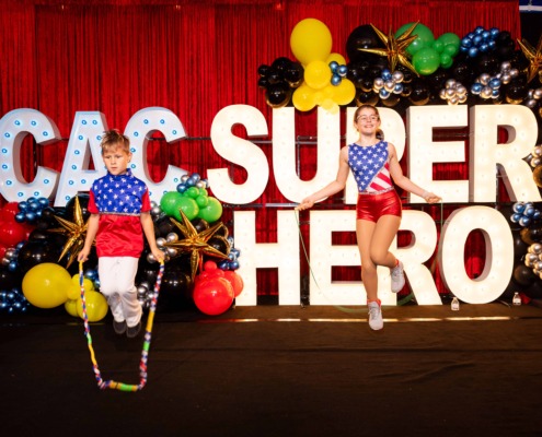 Colorful circus stage with balloons and large illuminated "CIRCUS" sign, featuring children jumping rope.
