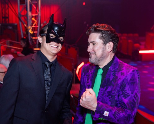 Batman mask performer at circus event, vibrant colors and stage lighting.