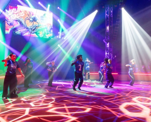 Colorful circus staging with dynamic lighting and performers on stage for a lively show.
